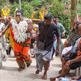 Hindu devotee climbing stairs toward Waterfall Hilltop Temple in Penang, Malaysia, carrying idumban kavadi (pole) and koodam mulle (torso pierced with shells), in honor of Lord Murugan for Thaipusam; photo by Ivan Kralj.