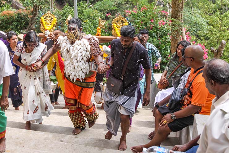 Hindu devotee climbing stairs toward Waterfall Hilltop Temple in Penang, Malaysia, carrying idumban kavadi (pole) and koodam mulle (torso pierced with shells), in honor of Lord Murugan for Thaipusam; photo by Ivan Kralj.