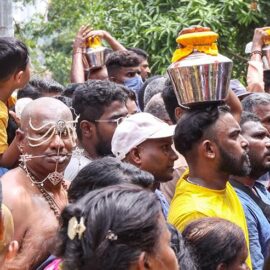 A crowd of Hindu devotees climbing toward Waterfall Hilltop Temple, some with facial piercings, some carrying milk pots (paal kudam) on their heads, for Thaipusam, Penang, Malaysia; photo by Ivan Kralj.