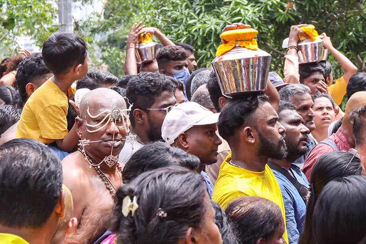 A crowd of Hindu devotees climbing toward Waterfall Hilltop Temple, some with facial piercings, some carrying milk pots (paal kudam) on their heads, for Thaipusam, Penang, Malaysia; photo by Ivan Kralj.