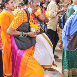 An older Hindu woman carrying a milk pot (paal kudam) in her arms as she climbs the stairs to Waterfall Temple during Thaipusam Festival in Penang, Malaysia; photo by Ivan Kralj.