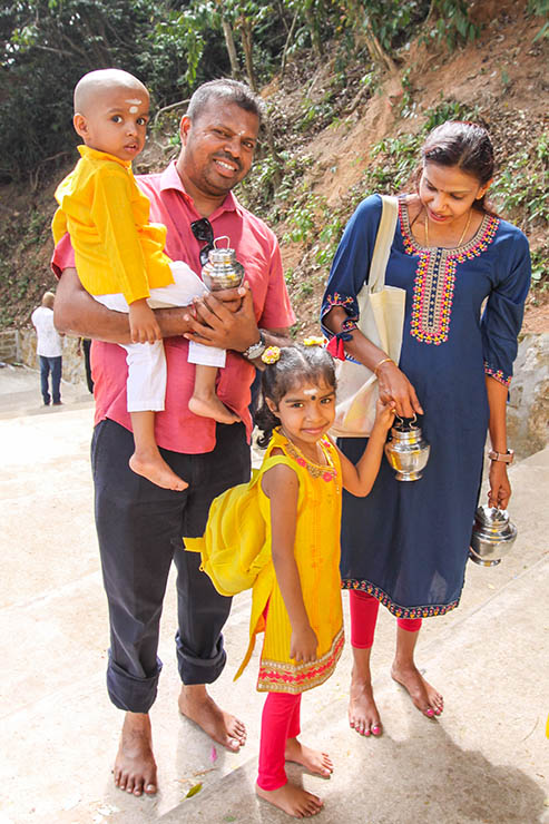 A smiling Hindu family, parents with a girl and a boy, carrying milk pots (paal kudam) for Thaipusam in Penang, Malaysia; photo by Ivan Kralj.