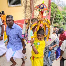 A young boy carrying a thol kavadi on his shoulders up the stairs during Thaipusam in Penang, Malaysia; photo by Ivan Kralj.