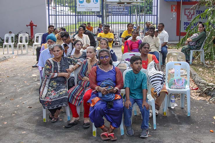 Hindu devotees of different generations sitting in plastic chairs during Thaipusam in Penang, Malaysia; photo by Ivan Kralj.