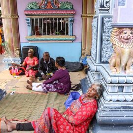 A tired woman resting her head on the wall of the Hindu temple during Thaipusam in Penang, Malaysia; photo by Ivan Kralj.
