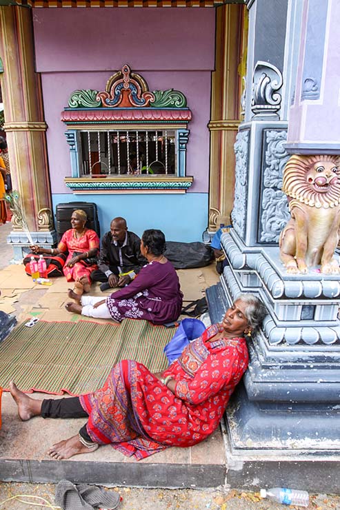A tired woman resting her head on the wall of the Hindu temple during Thaipusam in Penang, Malaysia; photo by Ivan Kralj.