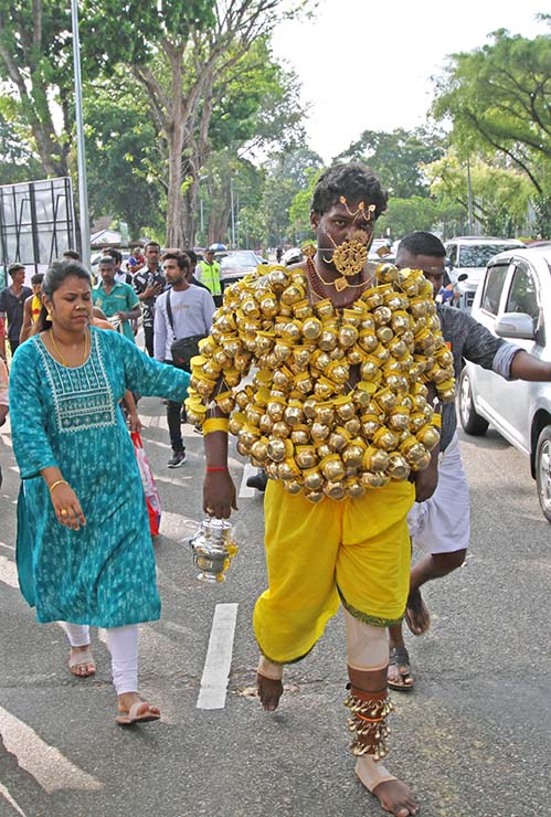 Hindu devotee carrying koodam mulle kavadi - milk pots pierced on his torso, and with forehead and cheeks pierced with little spears (alavu kavadi) in honor of Lord Murugan, during Thaipusam Festival in Penang, Malaysia; photo by Ivan Kralj.