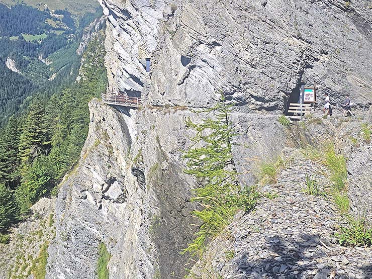 People walking on the edge of the exposed cliff during the Bisse du Torrent Neuf hike in Saviese, Switzerland; photo by Ivan Kralj.