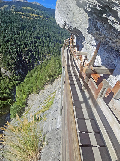 Wooden construction of Bisse du Torrent Neuf, attached to the rock face of the mountain in Swiss Alps, Saviese, with a view of the forested Morge Valley; photo by Ivan Kralj.
