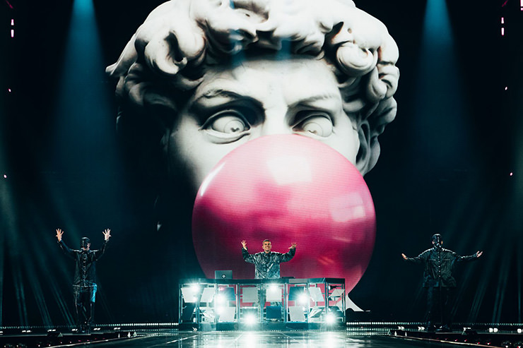 Gabry Ponte DJ-in on Eurovision stage in Basel, Switzerland, with Michelangelo's David blowing a giant bubblegum in the background; photo by Sarah Louise Bennett / EBU.