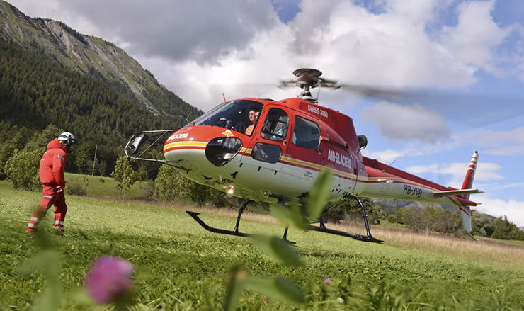 Red helicopter landing at Binii, the drop-off point for hikers who prefer to return from the Bisse du Torrent Neuf trail by air.