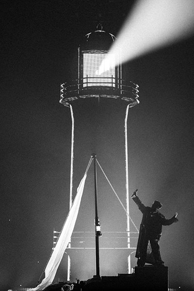 JJ performing "Wasted Love", an Austrian act on Eurovision, presented in black and white, with a boat on stage welcomed by a lighthouse as a symbol of hope; photo by Sarah Louise Bennett / EBU.