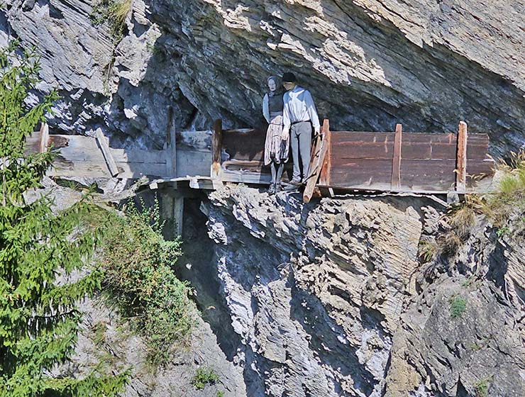 Human-sized dolls standing on the edge of the cliff at a reconstruction of the Bisse du Torrent Neuf traditional irrigational canal hanging directly on the mountain wall, in Saviese, Switzerland; photo by Ivan Kralj.