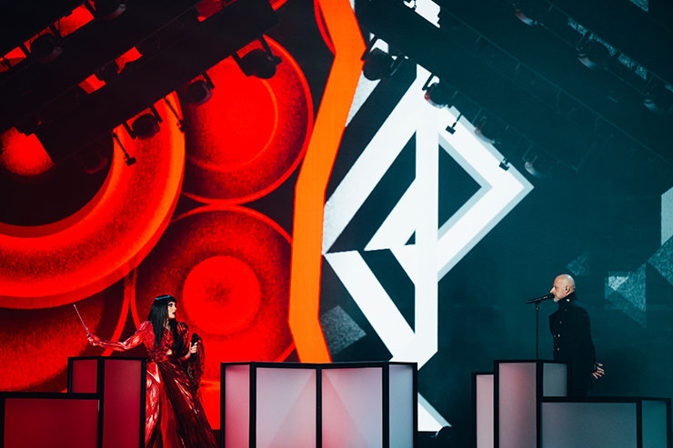 Shkodra Elektronike performing "Zjerm" for Albania at Eurovision Song Contest in Basel, Switzerland, with a stage split on red and black; photo by Sarah Louise Bennett / EBU.