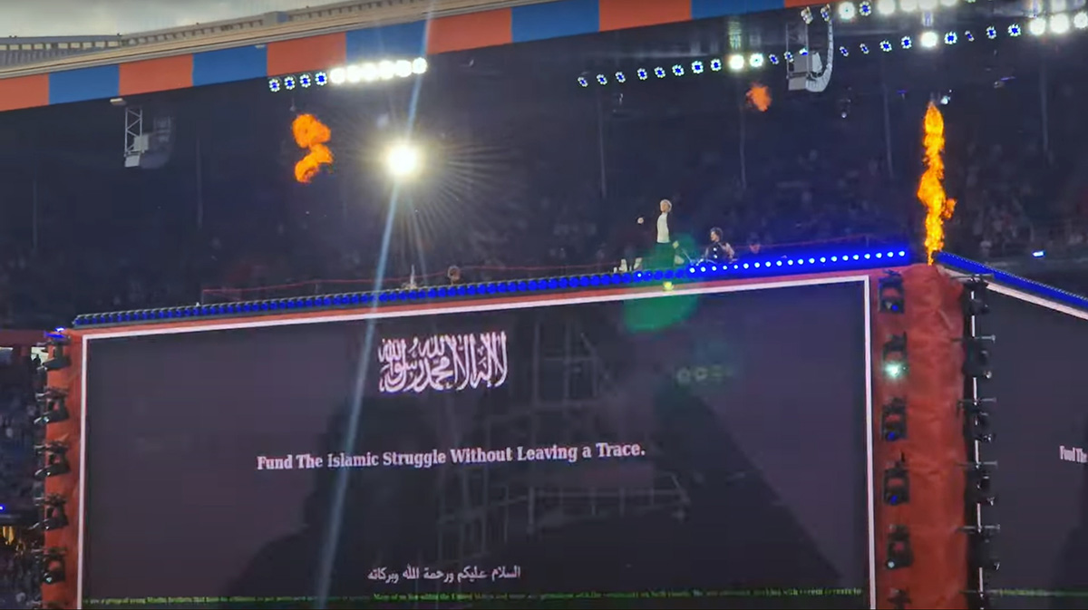 A screenshot of Baby Lasagna band performing "Rim Tim Tagi Dim" in Arena Plus, during a Eurovision pre-show at St. Jakob-Park stadium, atop a cube stage that displayed the message "Fund the Islamic Struggle Without Leaving a Trace"; screenshot from Luca's Space YouTube footage (00:35 of the song) by Pipeaway.