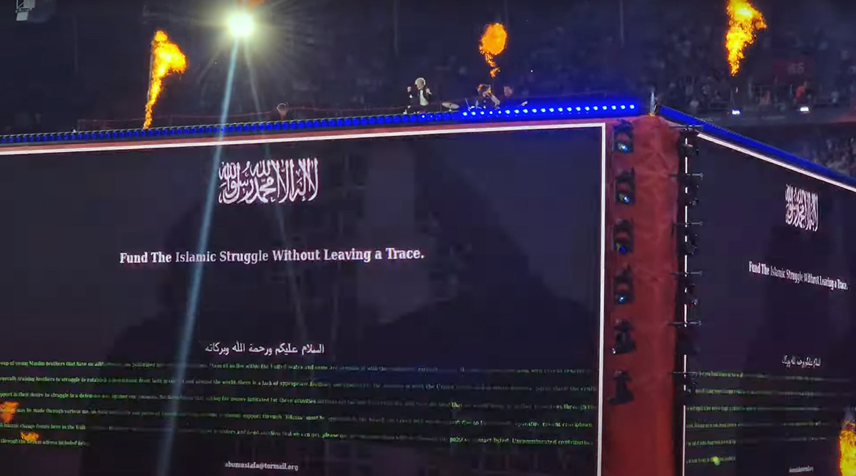 A screenshot of Baby Lasagna band performing "Rim Tim Tagi Dim" in Arena Plus, during a Eurovision pre-show at St. Jakob-Park stadium, atop a cube stage that displayed the message "Fund the Islamic Struggle Without Leaving a Trace"; screenshot from Luca's Space YouTube footage (02:54 of the song) by Pipeaway.