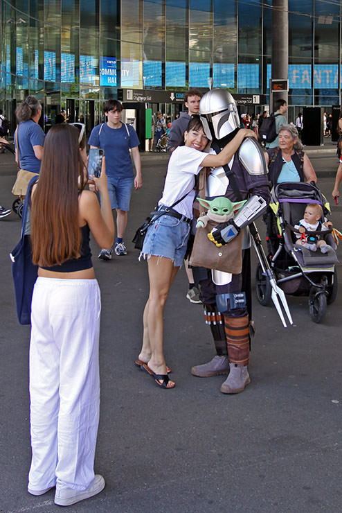 A woman hugging Din Djarin (Mandalorian) carrying Din Grogu (Baby Yoga) in his bag, at Fantasy Basel, the Swiss Comic Con; photo by Ivan Kralj.