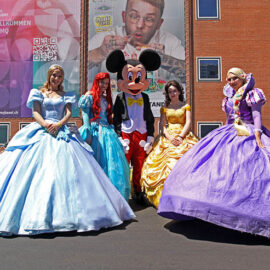 Cosplayers dressed up as Disney princesses Cinderella, Ariel, Belle, and Rapunzel, standing around Mickey Mouse, at Fantasy Basel, the Swiss Comic Con; photo by Ivan Kralj.