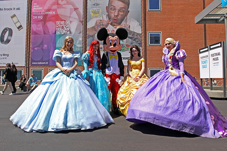 Cosplayers dressed up as Disney princesses Cinderella, Ariel, Belle, and Rapunzel, standing around Mickey Mouse, at Fantasy Basel, the Swiss Comic Con; photo by Ivan Kralj.