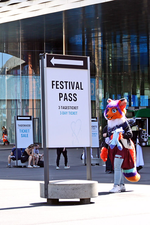 Fox furry cosplayer passing by the "Festival Pass" sign at Fantasy Basel, the Swiss Comic Con; photo by Ivan Kralj.