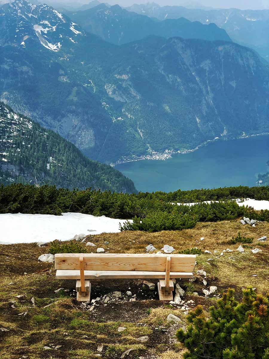 A bench on the Krippenstein mountain plateau with a view of the Lake Hallstatt at the foothill, Austria; photo by Victor Malyushev / Unsplash.