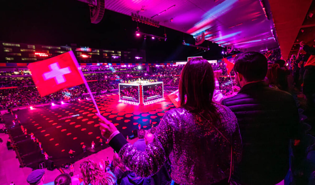 A visitor waving a Swiss flag at St. Jakob-Park stadium, the venue of Arena Plus pre-Eurovision party in Basel, Switzerland; photo by Mood Studios AG, Kanton Basel Stadt.