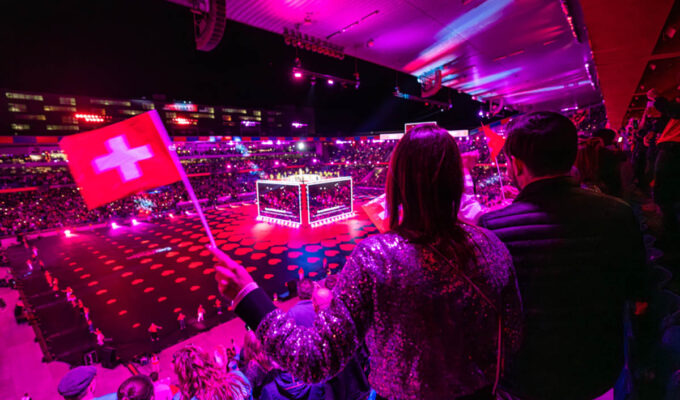 A visitor waving a Swiss flag at St. Jakob-Park stadium, the venue of Arena Plus pre-Eurovision party in Basel, Switzerland; photo by Mood Studios AG, Kanton Basel Stadt.