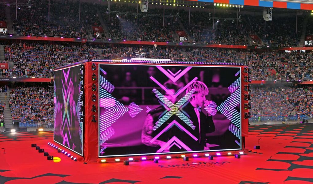 A giant screen-cube displaying Croatian musician Baby Lasagna performing at St. Jakob-Park stadium in Basel, Switzerland, during the Arena Plus Eurovision pre-show; photo by Ivan Kralj.