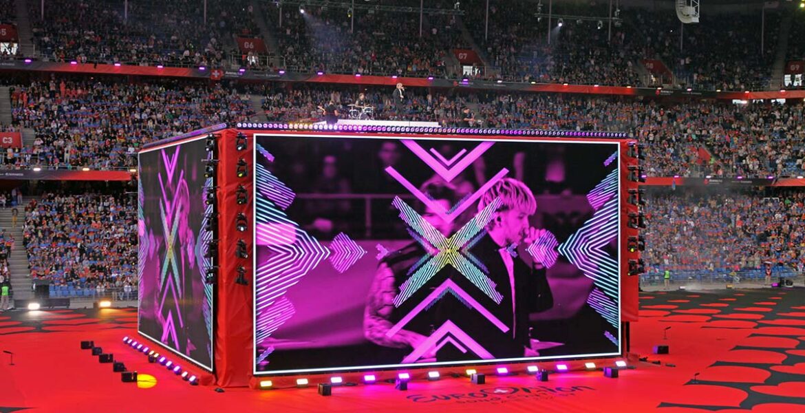 A giant screen-cube displaying Croatian musician Baby Lasagna performing at St. Jakob-Park stadium in Basel, Switzerland, during the Arena Plus Eurovision pre-show; photo by Ivan Kralj.