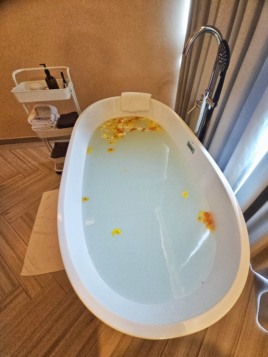 Freestanding bathtub filled with milky bath covered in floral petals at the Cave Spa at Hilltop Wellness Resort in Phuket, Thailand; photo by Ivan Kralj.