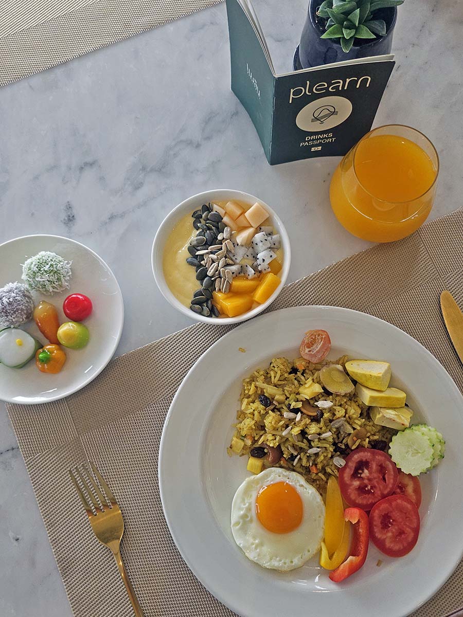Breakfast at Plearn Restaurant, Hilltop Wellness Resort, Phuket, shot from above - traditional Thai sweets, smoothie bowl, orange juice, and rice with vegetables, tofu, and sunny-side-up egg; photo by Ivan Kralj.
