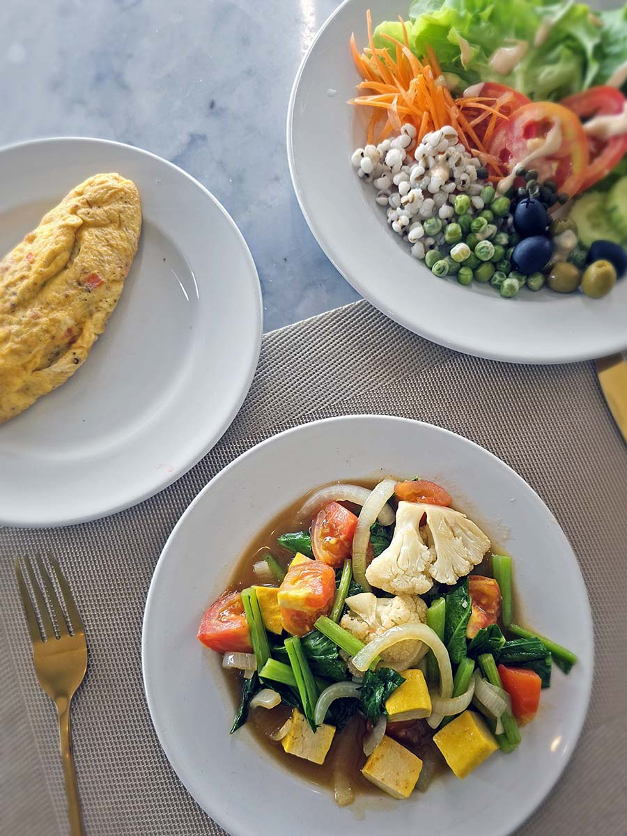 Top view of the plated breakfast options (salad, omelette, veggies with tofu) served at the Plearn Restaurant at Hilltop Wellness Resort in Phuket, Thailand; photo by Ivan Kralj.