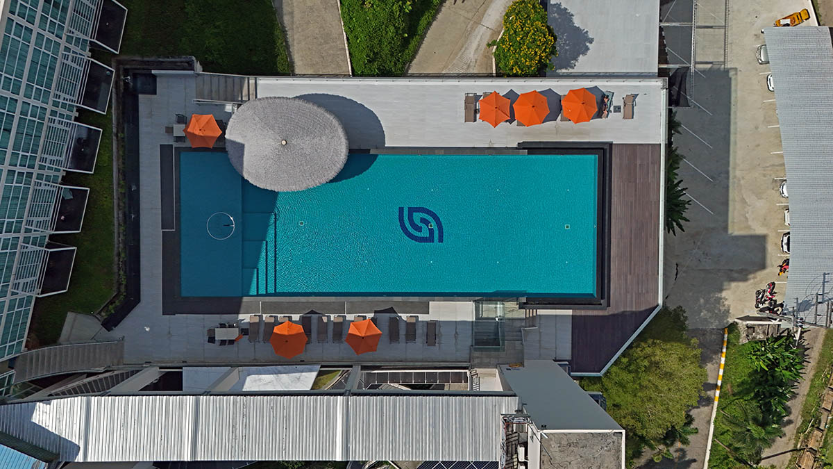 Blue infinity pool with orange parasols shot from above, at Hilltop Wellness Resort in Phuket, Thailand; drone photo by Ivan Kralj.
