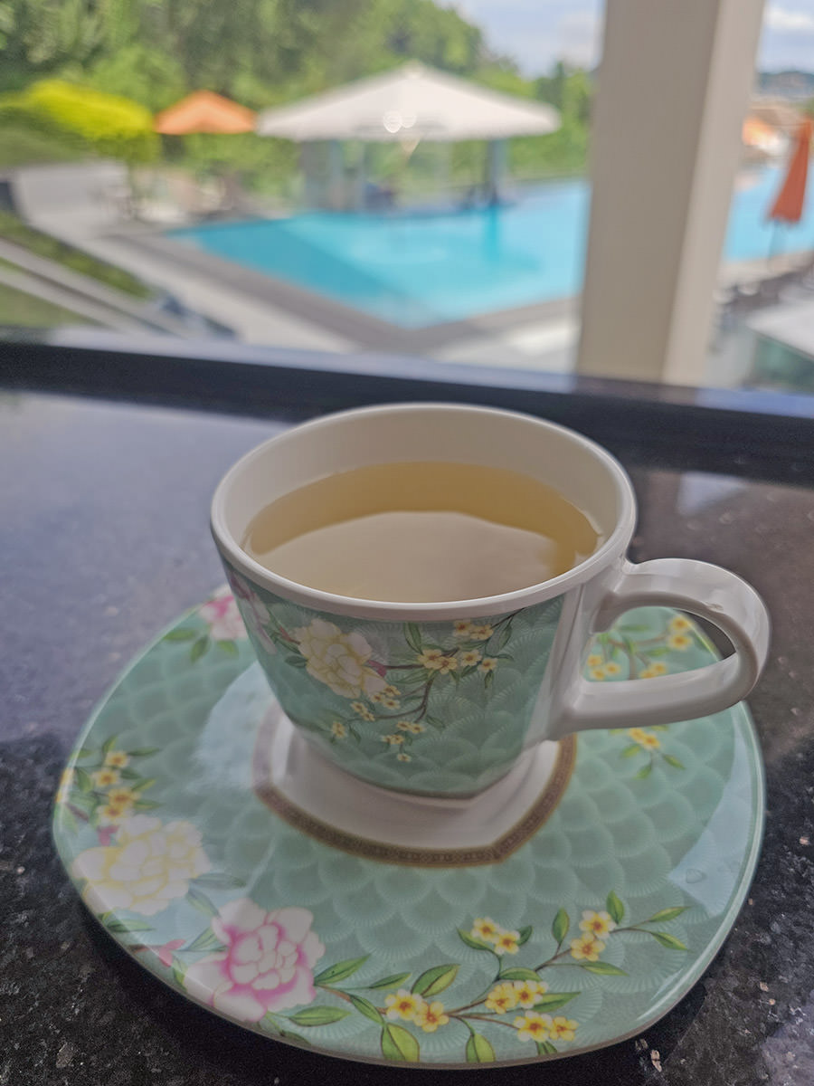 A cup of tea with a swimming pool in the blurred background at Hilltop Wellness Resort in Phuket, Thailand; photo by Ivan Kralj.