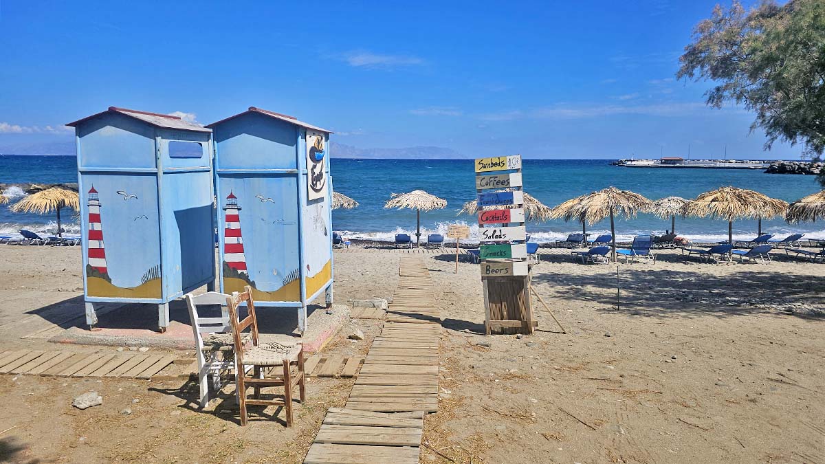 Colorful changing cabins, parasols, and sunbeds on Agia Pelagia Beach in Kythira, Greece; photo by Ivan Kralj.