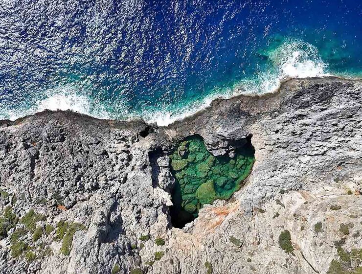 Bird's-eye view of the heart-shaped Green Lake or Prasini Limni on the rugged rocky coastline of Kythira Island in Greece; drone photo by Ivan Kralj.