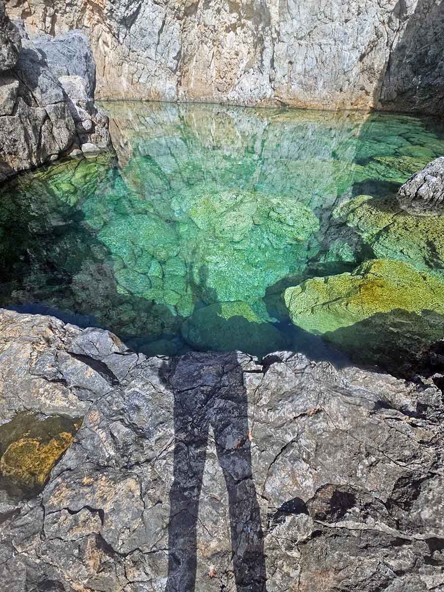 Shadow of the travel blogger Ivan Kralj on green surface of the Prasini Limni lake/lagoon shaped like a heart on Kythira Island, Greece; photo by Ivan Kralj.