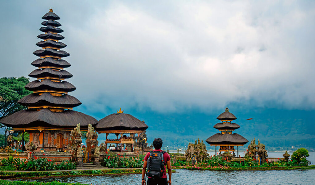 A traveler standing in front of the Pura Ulun Danu Bratan water temple in Bali, Indonesia; photo by Santhosh Mocharla, Unsplash.