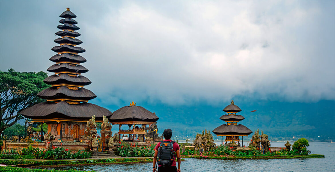 A traveler standing in front of the Pura Ulun Danu Bratan water temple in Bali, Indonesia; photo by Santhosh Mocharla, Unsplash.