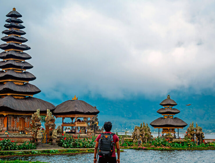 A traveler standing in front of the Pura Ulun Danu Bratan water temple in Bali, Indonesia; photo by Santhosh Mocharla, Unsplash.