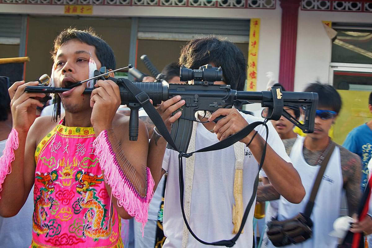 One of Kathu Shrine's ma song, spirit mediums, parading with a machine gun piercing his cheeks during the annual Phuket Vegetarian Festival 2011; photo by Joseph Ferris III.