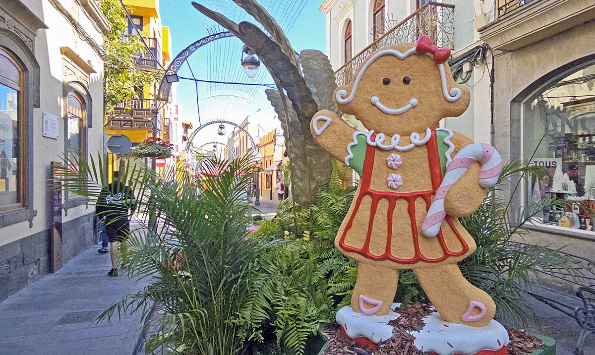 Female-decorated gigantic cookie waving hand in Calle Larga, Gáldar, as one of the floral allegories decorating the street of Ciudad de la Navidad, Gran Canaria's City of Christmas; photo by Ivan Kralj. 