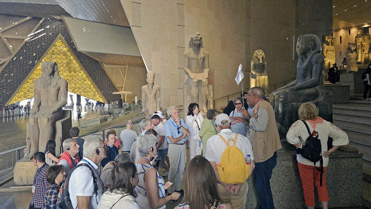 A group tour with a guide standing on the Grand Stairs of the Grand Egyptian Museum in Giza, Egypt; photo by Ivan Kralj.