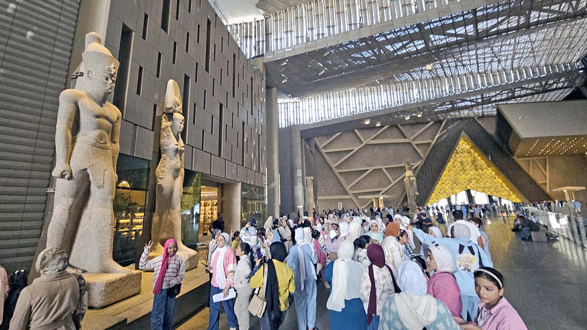 Colossal statues of Ptolemaic King and Queen, exhibited in the atrium of the Grand Egyptian Museum in Giza, Egpyt, surrounded by visitors; photo by Ivan Kralj.