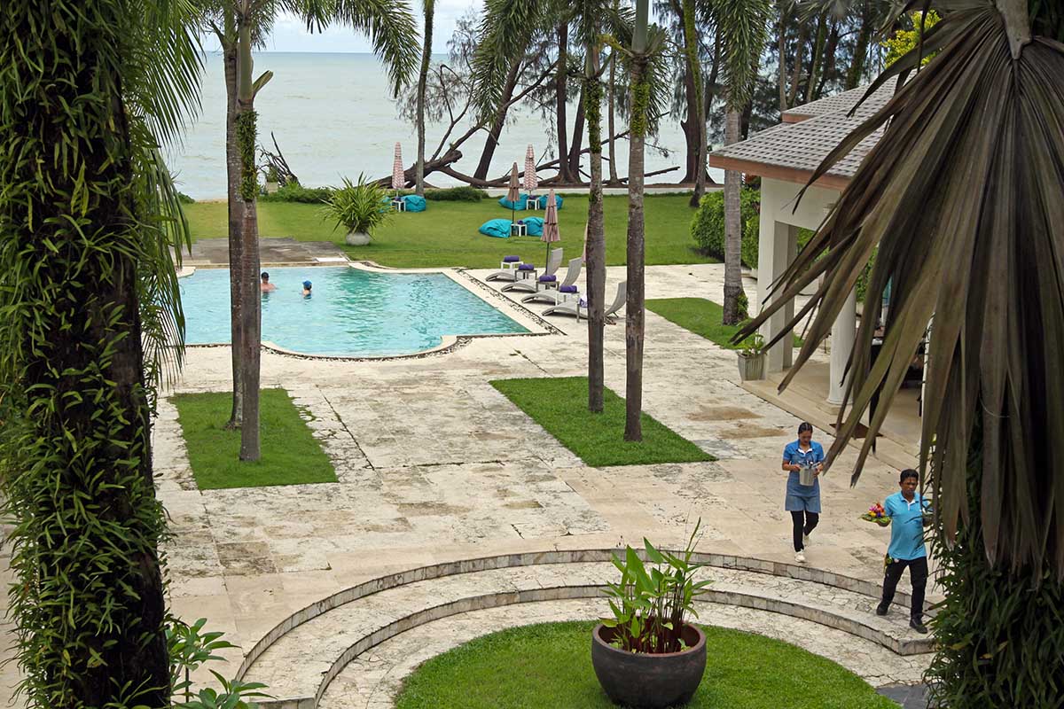People enjoying a swimming pool with sea view at Anda Mani Khaolak Beachfront Villas in Phang Nga, Thailand, with service staff bringing fruit and sparkling wine; photo by Ivan Kralj.