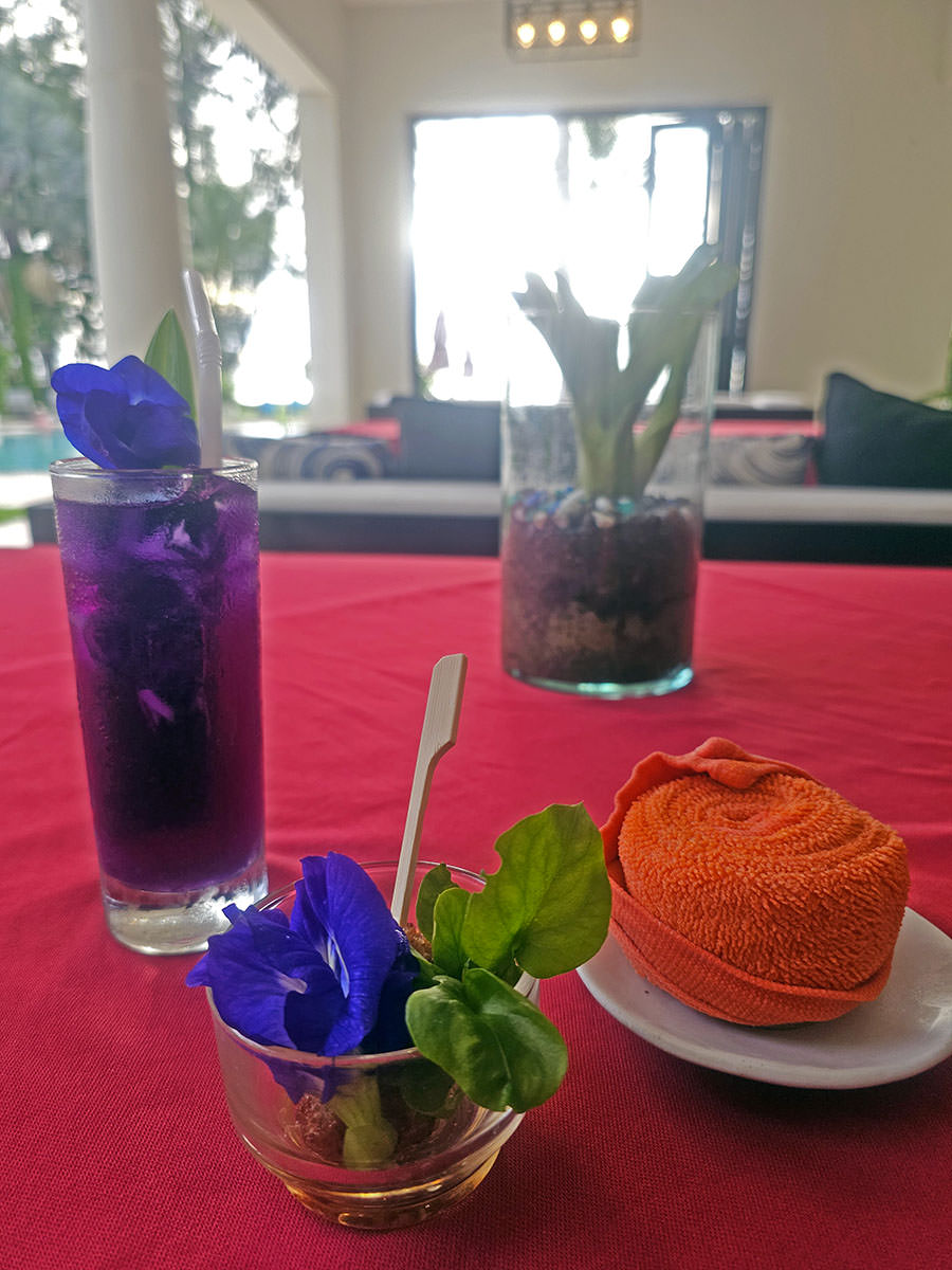 Welcome service at Anda Mani Khao Lak Beachfront Villas includes a glass of homegrown butterfly pea flower juice, a small skewered treat, and a refreshing towel; photo by Ivan Kralj.