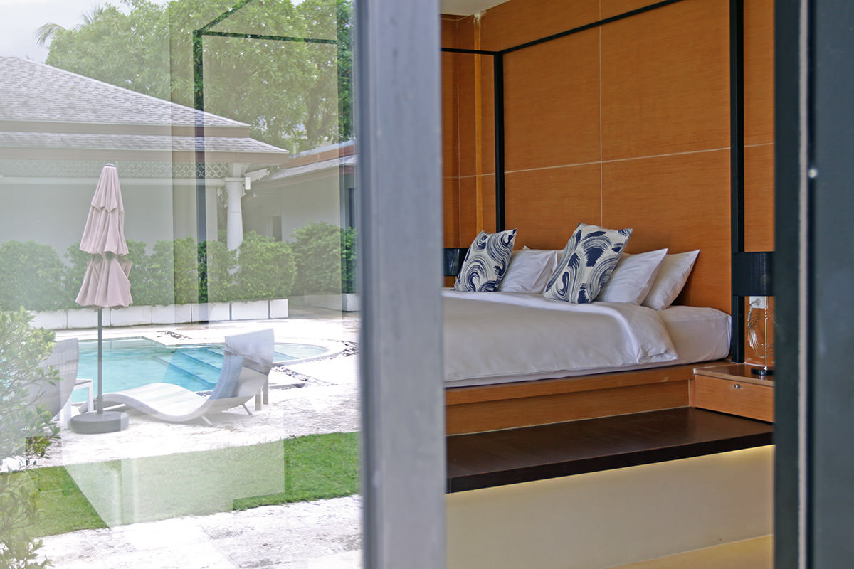 Peak into the Oceanfront Villa's bedroom, with resort's swimming pool reflecting in the window at Anda Mani Khao Lak, Thailand; photo by Ivan Kralj.