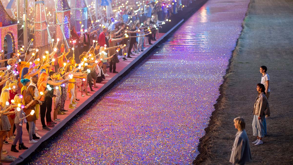 Colorful partygoers divided by a moat, river of sequins, from the colorless observers; AI illustration of Eurovision Song Contest Live Tour focusing solely on Western Europe - AI image by Ivan Kralj, Reve.