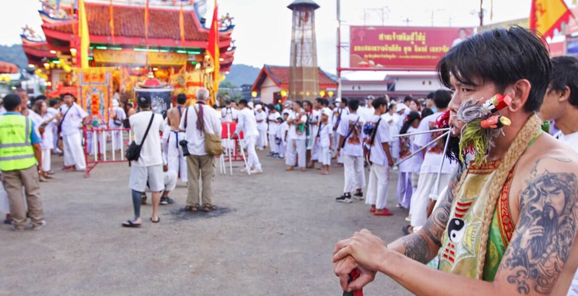 Ma song participant of the Phuket Vegetarian Festival, his cheeks pierced by spikes, standing in front of the Lim Hu Tai Su Shrine; photo by Ivan Kralj.
