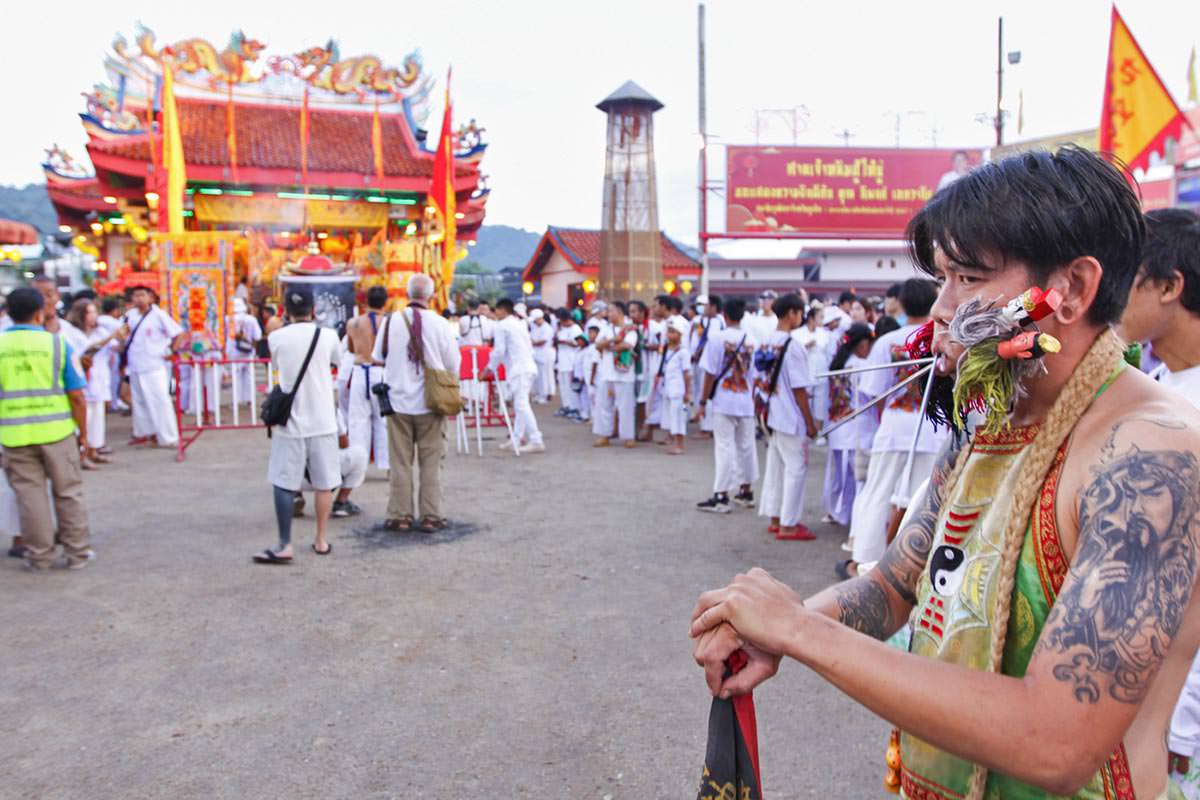 Ma song participant of the Phuket Vegetarian Festival, his cheeks pierced by spikes, standing in front of the Lim Hu Tai Su Shrine; photo by Ivan Kralj.